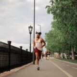 Persoană care aleargă pe o stradă liniștită a orașului la răsărit, cu lumina caldă a dimineții în fundal