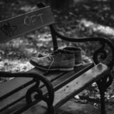 Pereche de pantofi de alergare legați, așezați pe o bancă din parc, într-o dimineață însorită
