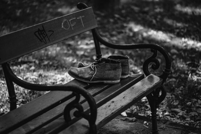 Pereche de pantofi de alergare legați, așezați pe o bancă din parc, într-o dimineață însorită